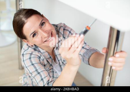 young woman using screwdriver to install kitchen furniture Stock Photo
