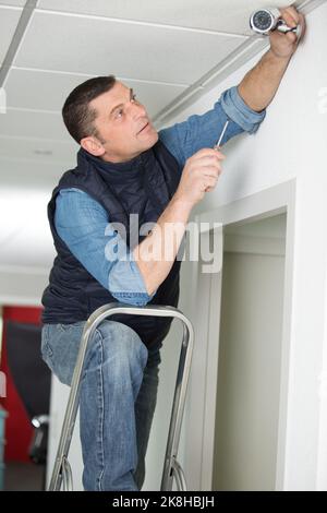 man install surveillance ip camera for home security Stock Photo