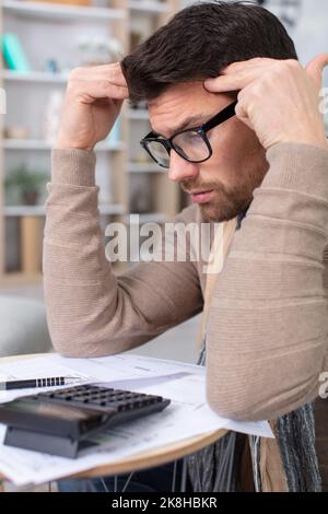 man troubled doing his home accounts Stock Photo