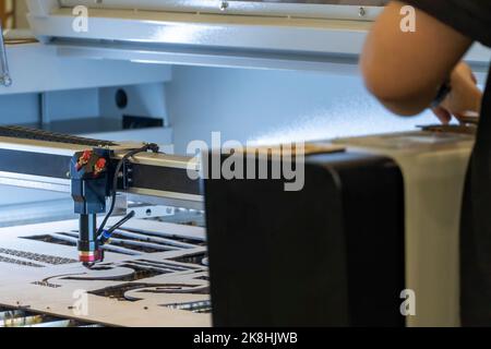 laser cutting machine, cutting wood sheets, while a man records the process, mexico Stock Photo
