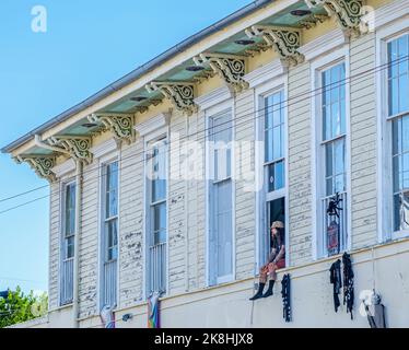 NEW ORLEANS, LA, USA - OCTOBER 22, 2022: Man sitting in 2nd floor window of the historic Bargain Center building with his legs hanging out Stock Photo