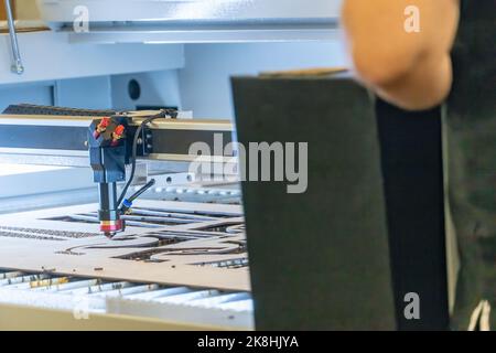 laser cutting machine, cutting wood sheets, while a man takes care of the process, latin america Stock Photo