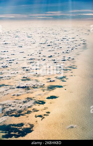 A layer of scattered cumulus clouds from above, with the warm late afternoon sunlight reflected in the South China Sea Stock Photo