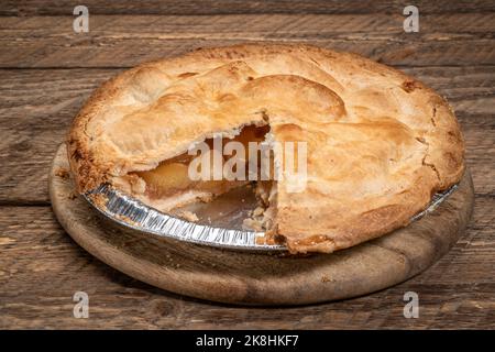 freshly baked apple pie on in an aluminum tray with piece taken Stock Photo