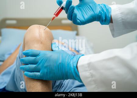 Asian doctor inject Hyaluronic acid platelet rich plasma into the knee of senior woman to walk without pain. Stock Photo