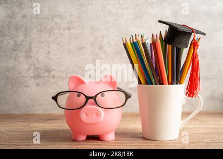 Pigging bank wearing eyeglass with colorful pencils; saving bank education concept. Stock Photo