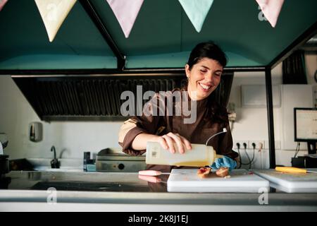 Woman smiling while preparing food in a restaurant kitchen. Stock Photo