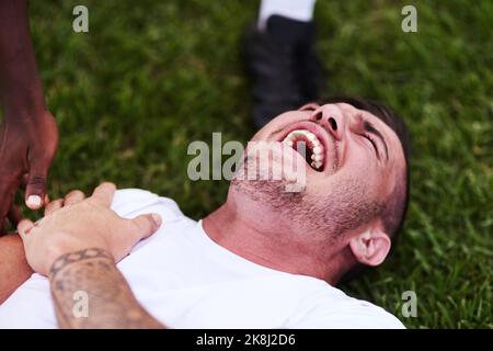 Collision sport comes with a risk. a young man screaming in pain after injuring himself during a rugby game. Stock Photo