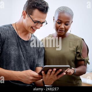 Its the commitment of a team that matters. two businesspeople working together on a digital tablet in an office. Stock Photo