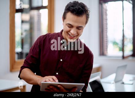 Ill find what I need online. a young businessman using a digital tablet in an office. Stock Photo