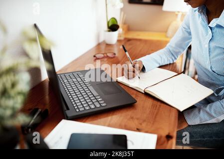Productivity and a good plan go hand in hand. a businesswoman writing financial data in a notebook at her desk. Stock Photo