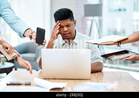 Being overwhelmed at work can hurt your productivity and your health. a young businessman looking stressed out in a demanding office environment. Stock Photo