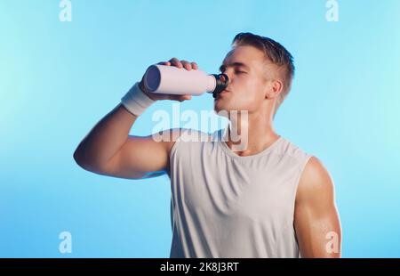 Time to hydrate. Studio shot of a handsome young man drinking from a water bottle against a blue background. Stock Photo