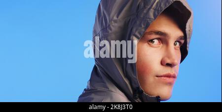 Nothing gets in the way of a good workout. Studio portrait of a handsome young man posing in a hooded sweater against a blue background. Stock Photo
