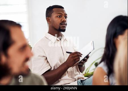 Hes really invested and inspired by this seminar. a young businessman writing notes during a conference. Stock Photo