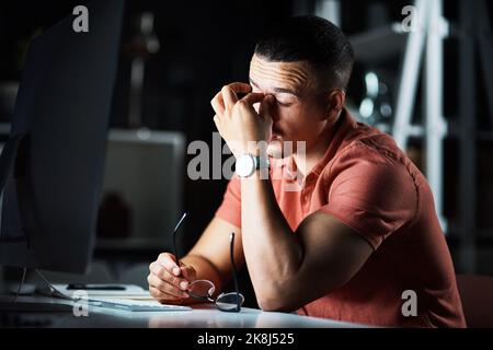 Im tired but Ive got to reach deadline. a businessman looking tired while working late at the office. Stock Photo