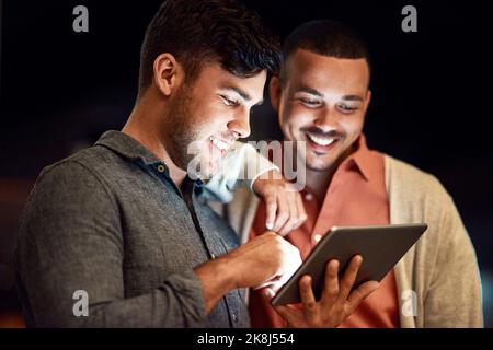 You have access to anything. two businessmen looking at a digital tablet while standing outside at night. Stock Photo
