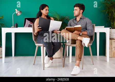 Ensuring their designs cater for the global market. two young designers having a discussion in an office. Stock Photo