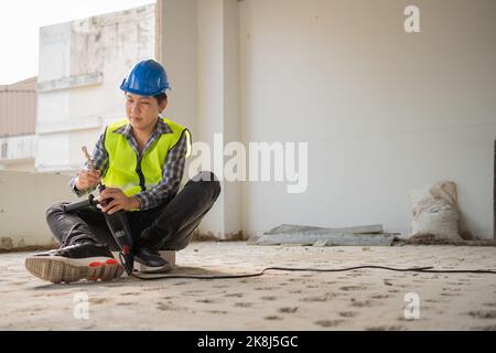 Construction worker Using an electric jackhammer to drill perforator equipment making holes before pouring the floor to be strong at construction site Stock Photo