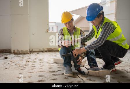 Engineer teaching worker for use electric jackhammer for perforator equipment making holes the floor to be strong at construction site, Concept of wor Stock Photo