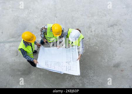 Top view of Asian engineer or Young Female Architect put on a helmet for safety and talk with a contractor on a construction building factory project, Stock Photo