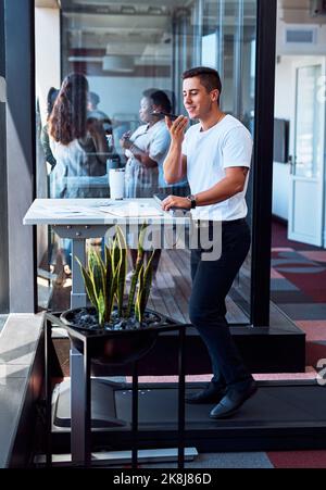 A treadmill desk can help you achieve more movement in your work day. a young businessman using a cellphone while walking on a treadmill in an office. Stock Photo