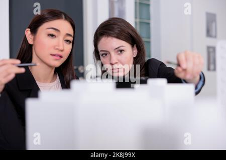 Architects discussing building printed 3d model, looking at prototype in coworking space, front view. Employees in architecture office selective focus, real estate agency project Stock Photo