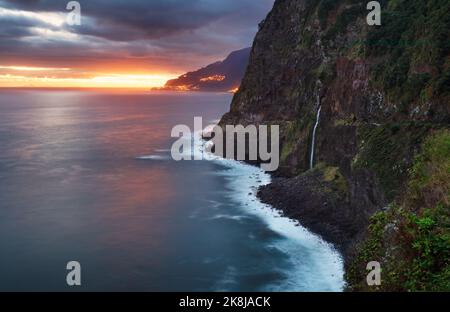 Madeira island - Dramatic sunrise over atlantic ocean with waterfall landscape from Miradouro do Veu da Noiva Stock Photo