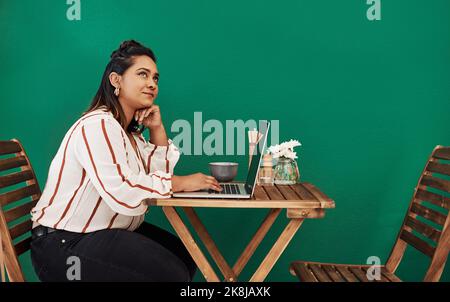 Have you subscribed to her awesome blog yet. a young woman looking thoughtful while using a laptop at a cafe. Stock Photo