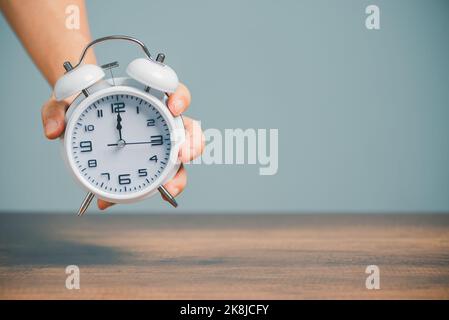 Time management for business, daily daily routine working job concept, Hand holding alarm ablove desk with copy space. Stock Photo