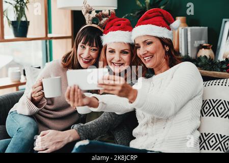 We did well on costumes. three attractive middle aged women taking self portraits together with a cellphone at home during Christmas time. Stock Photo