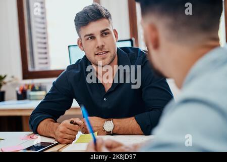 Do what you need to do to get it done. two young businessmen working together on a task in a modern office. Stock Photo