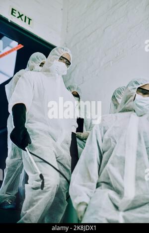 Send in the virus fighting troops. a group of healthcare workers wearing hazmat suits working together to control an outbreak. Stock Photo