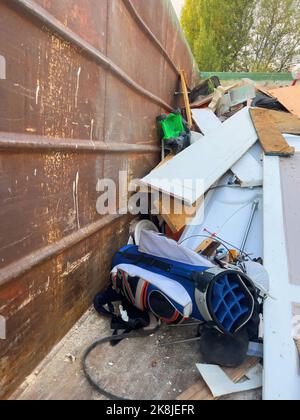 Paris, France- Oct 18, 2022: Recycling concept - throw away golf club bag in dumpster- recycling old objects Stock Photo