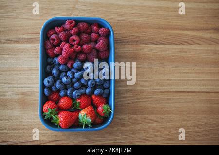 Fresh berries. Various summer berries, strawberries, blueberries and raspberries in bowl on rustic wooden background. Top view Stock Photo