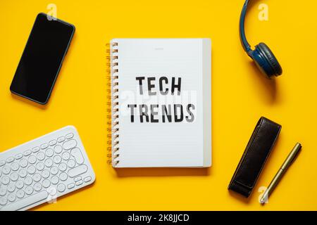 Tech trends, Top New Technology Trends. Word trends on open notepad with different gadgets and devices on yellow background. Stock Photo