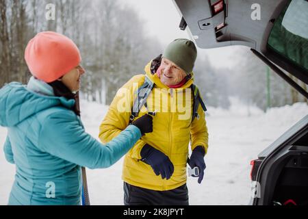 Senior couple near car trunk preparing for winter hiking. Stock Photo