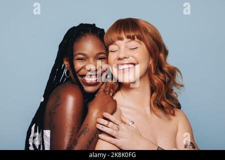 Cheerful young women with different skin tones smiling while standing together. Two happy young women feeling comfortable in their own skin. Body conf Stock Photo