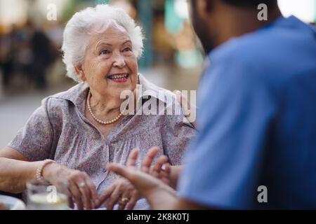Caregiver talking with his client at cafe, having nice time together. Stock Photo