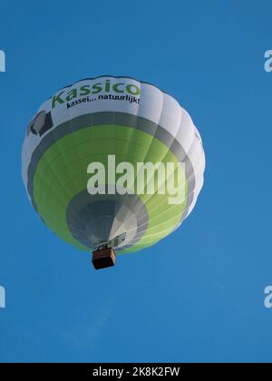 Sint Niklaas, Belgium, September 04, 2022, Green with white hot air balloon with a beautiful blue sky as background Stock Photo
