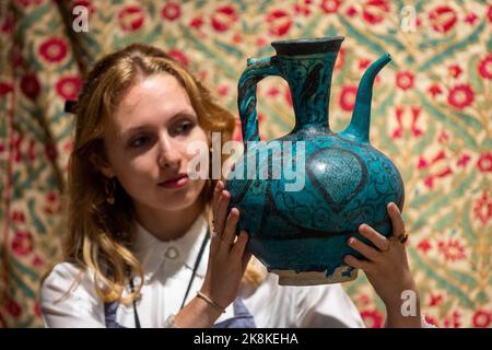 London, UK.  24 October 2022. A technician presents 'An underglaze painted pottery ewer' Persia or Syria, 13th/ 14th century (Est. £6,000 - £8,000) at the preview of Bonhams Islamic and Indian Art Sale.  157 lots are to be auctioned on 25 October at Bonham’s New Bond Street galleries  Credit: Stephen Chung / Alamy Live News Stock Photo