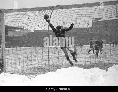 Oslo 19471115. Football in snowy weather at Bislett. The football match between Dynamo and Skeid was played on winter. Before and during the match it snowed tightly, and the grass mat was white and hard. 32,000 spectators are a record at Bislett. Here it is 'Skeids' keeper Knut Arnevaag who takes a great rescue. Photo: Current / NTB Stock Photo