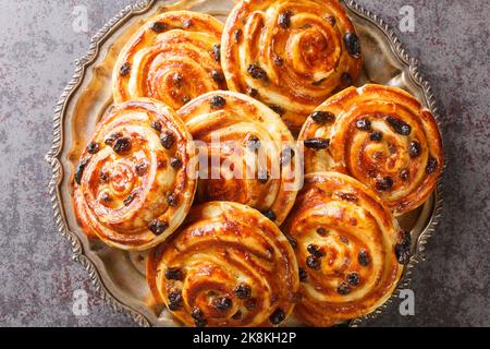 Pain aux raisin translates to bread with raisins or escargot, because of the snail-like shape of the little individual pastries closeup in the plate o Stock Photo
