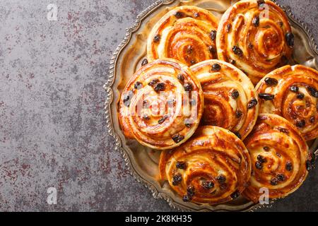 Delicious pain aux raisins spiral buns with raisins and custard close-up in a plate on the table. horizontal top view from above Stock Photo