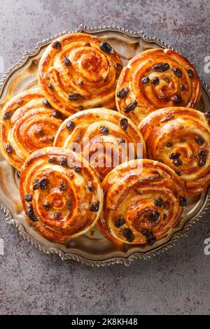 Pain aux Raisins, Danish raisin pastry swirls closeup in the plate on the table. Vertical top view from above Stock Photo
