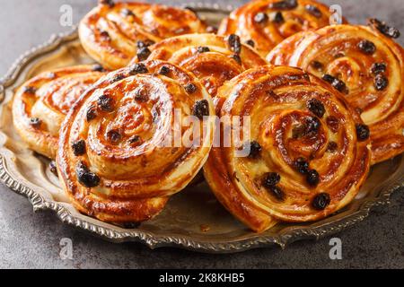 Pain aux raisin translates to bread with raisins or escargot, because of the snail-like shape of the little individual pastries closeup in the plate o Stock Photo