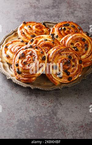 Pain aux Raisins, Danish raisin pastry swirls closeup in the plate on the table. Vertical Stock Photo