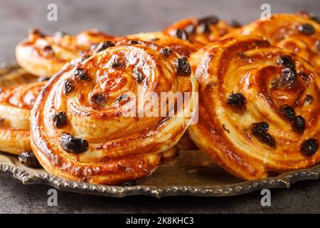 Delicious pain aux raisins spiral buns with raisins and custard close-up in a plate on the table. horizontal Stock Photo