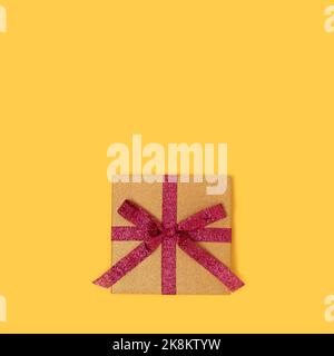 Gift box with red ribbon. Creative concept on a yellow background. Stock Photo