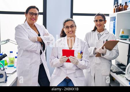 Three woman scientists using touchpad write on checklist at laboratory Stock Photo